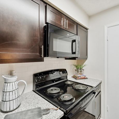Altamonte Apartments kitchen with granite counters, wooden cabinets, and modern appliances.